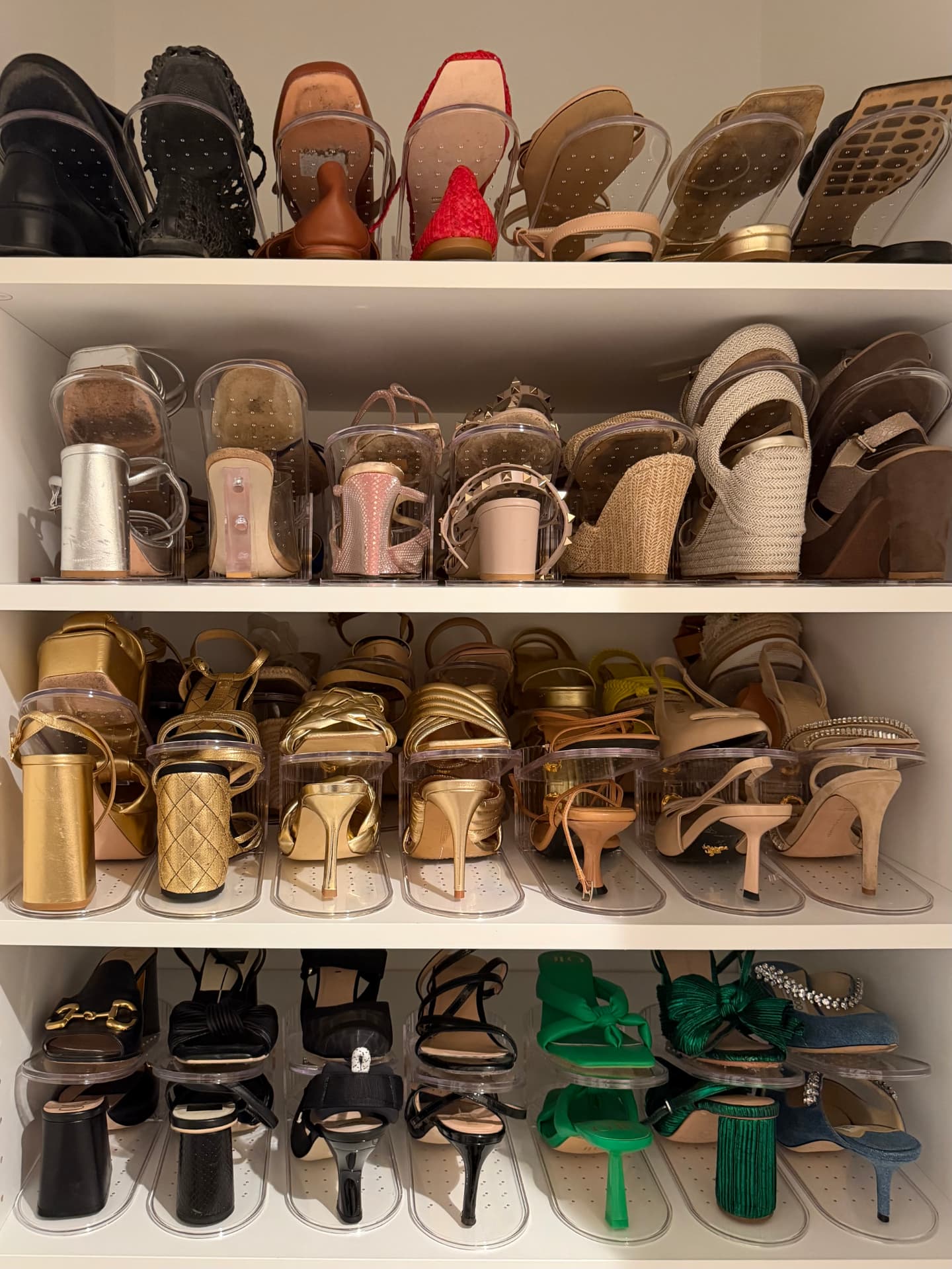 Shelves of heels, sandals, and wedges displayed upright on clear acrylic shoe risers
